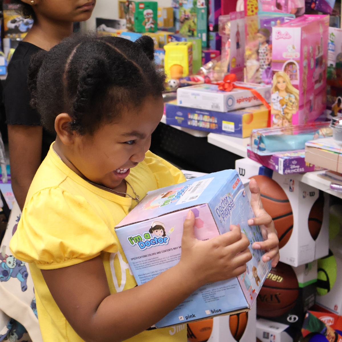 A child hugs a gift at SAY San Diego's Holiday Hopes toy shop